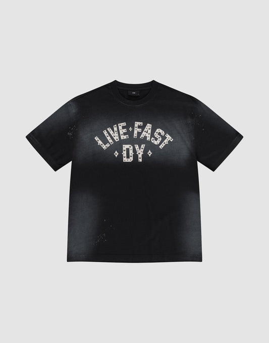 The Live Fast Rivet Tee by LIVE FAST DIE YOUNG is a black 100% Baumwolle shirt with a handgefertigter Sprayeffekt, faded finish, and bold "LIVE FAST DY" in white patterns across the chest. Displayed flat on a light gray background. | plain