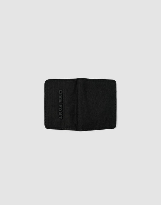The LFDY Cardholder by LIVE FAST DIE YOUNG is a black bifold wallet with card slots, shown open on a light gray background. "LIVE FAST" is embossed vertically on the left inner side.