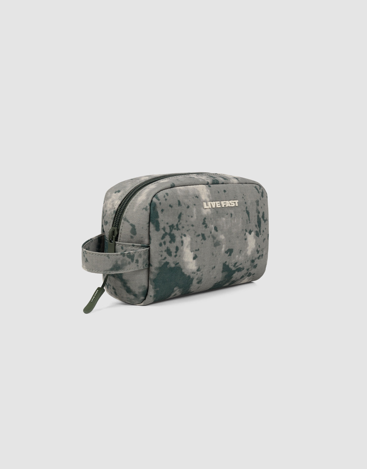 The LFDY Amenity Kit by LIVE FAST DIE YOUNG is a small rectangular toiletry bag with a camouflage pattern, 100% polyester, large zipper compartment, side handle, and “LIVE FAST” printed on the front. Plain light gray background.| plain 