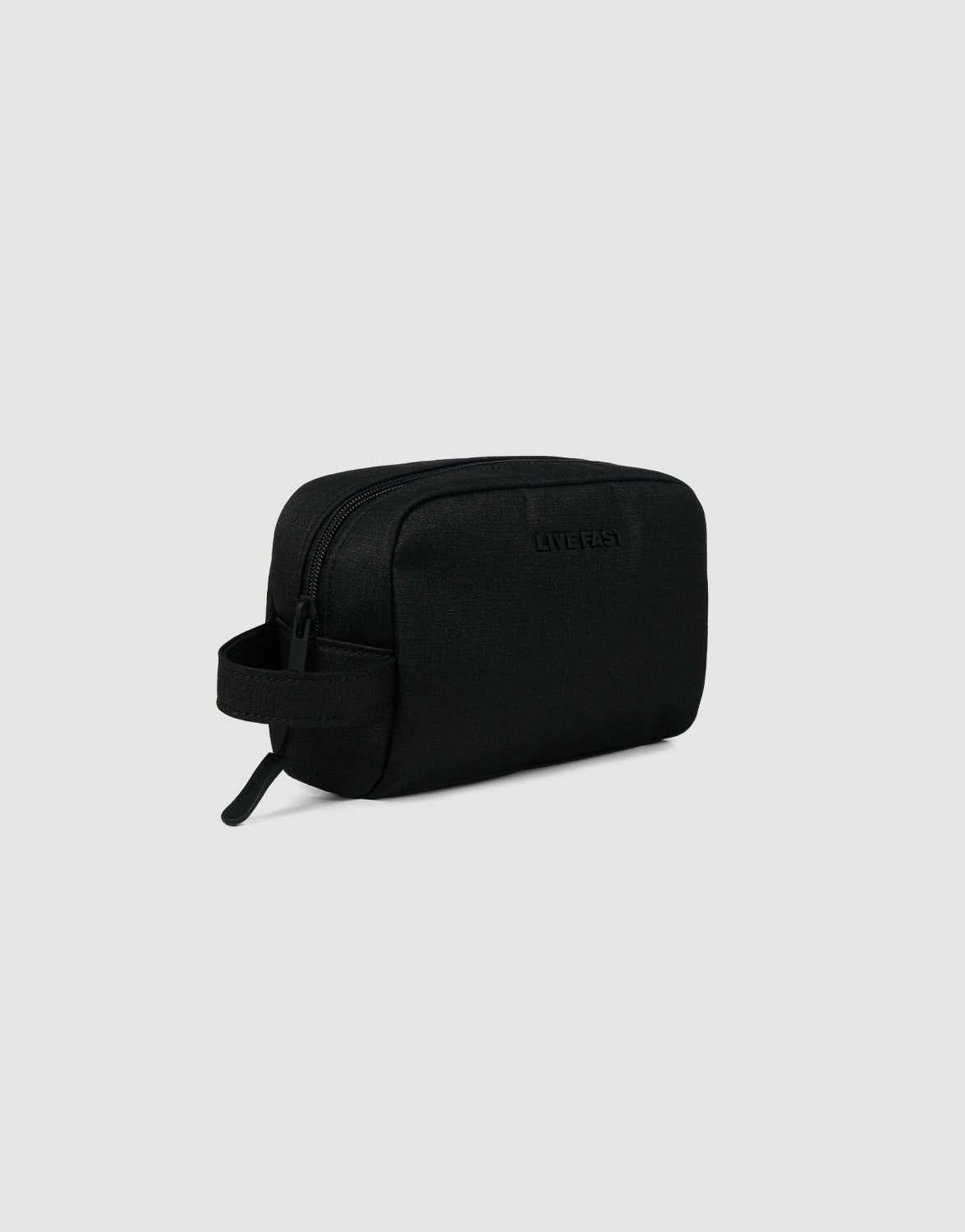 The LFDY Amenity Kit by LIVE FAST DIE YOUNG is a black rectangular toiletry bag made from durable polyester with a zipper closure, side handle, and large zip pocket, shown against a light gray background.| plain