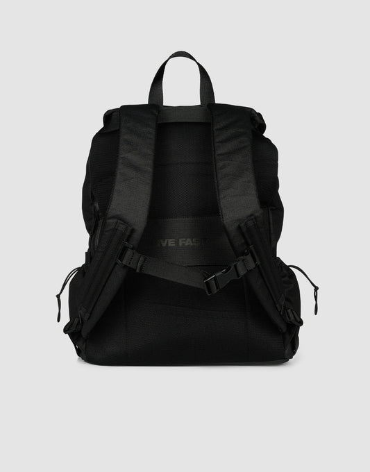 The LFDY Travel Backpack by LIVE FAST DIE YOUNG, in black, is shown from the back with adjustable shoulder straps, a top handle, zippered side pockets, an adjustable chest buckle, and 25L capacity against a plain light gray background.