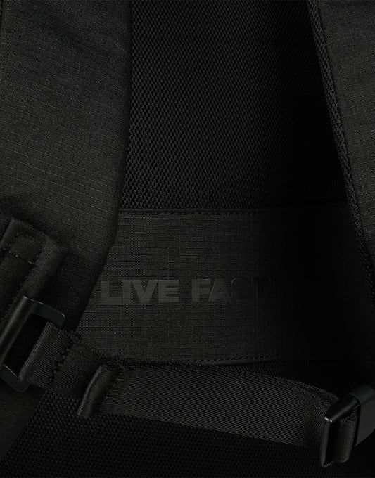 Close-up of the LFDY Travel Backpack (25L) by LIVE FAST DIE YOUNG, featuring padded mesh fabric, adjustable shoulder straps, a back strap, and the phrase LIVE FAST in subtle dark lettering.