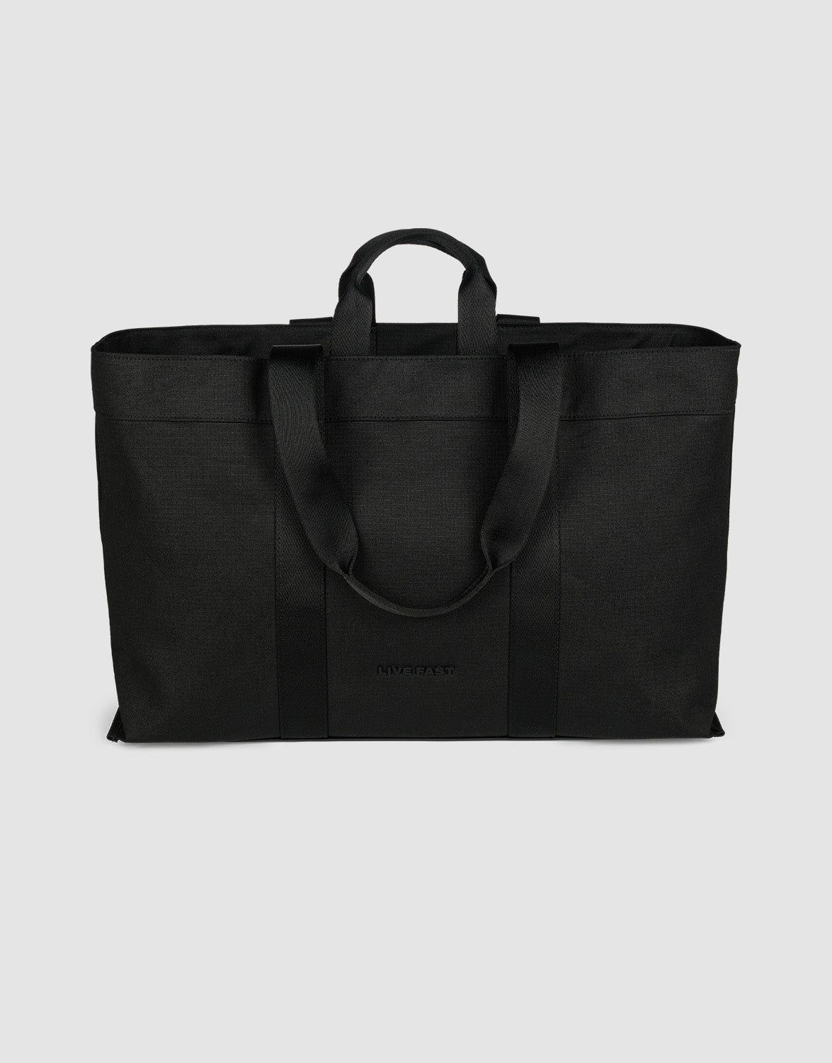 The LFDY Utility Bag by LIVE FAST DIE YOUNG is a large black tote with two short handles, two long shoulder straps, a spacious main compartment, and durable polyester construction, shown against a plain light gray background.| plain 