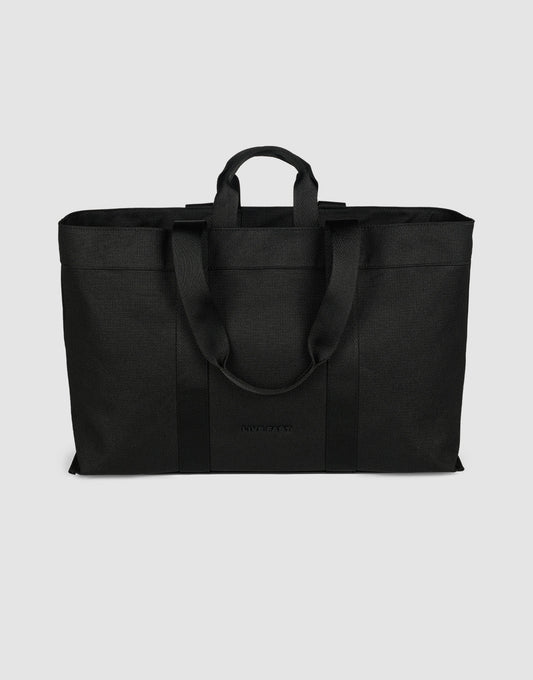 The LFDY Utility Bag by LIVE FAST DIE YOUNG is a large black tote with two short handles, two long shoulder straps, a spacious main compartment, and durable polyester construction, shown against a plain light gray background.| plain 