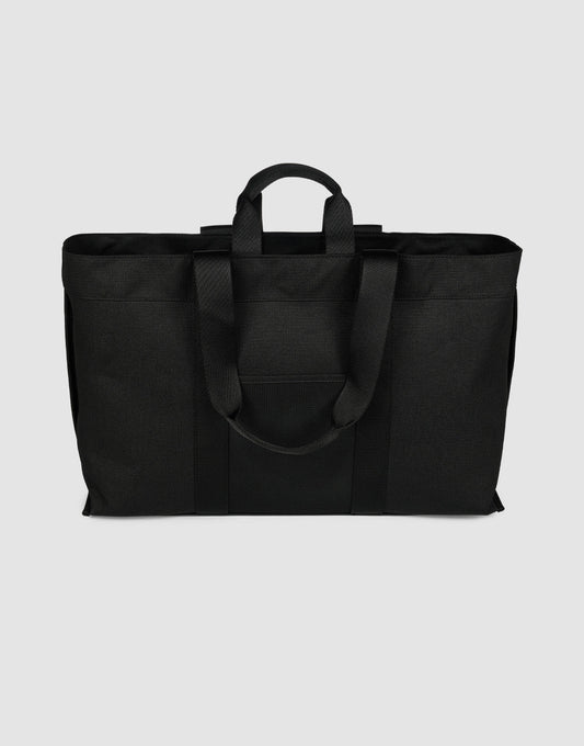 The LFDY Utility Bag by LIVE FAST DIE YOUNG is a black tote made of durable polyester, with two short handles, two long shoulder straps, and a spacious main compartment, shown on a plain light gray background.