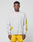 A man faces forward in a LIVE FAST DIE YOUNG LFDY Split Sphere Longsleeve—a light gray, oversized shirt with yellow designs and LIVIN text on the chest—paired with bright yellow shorts against a plain light background.