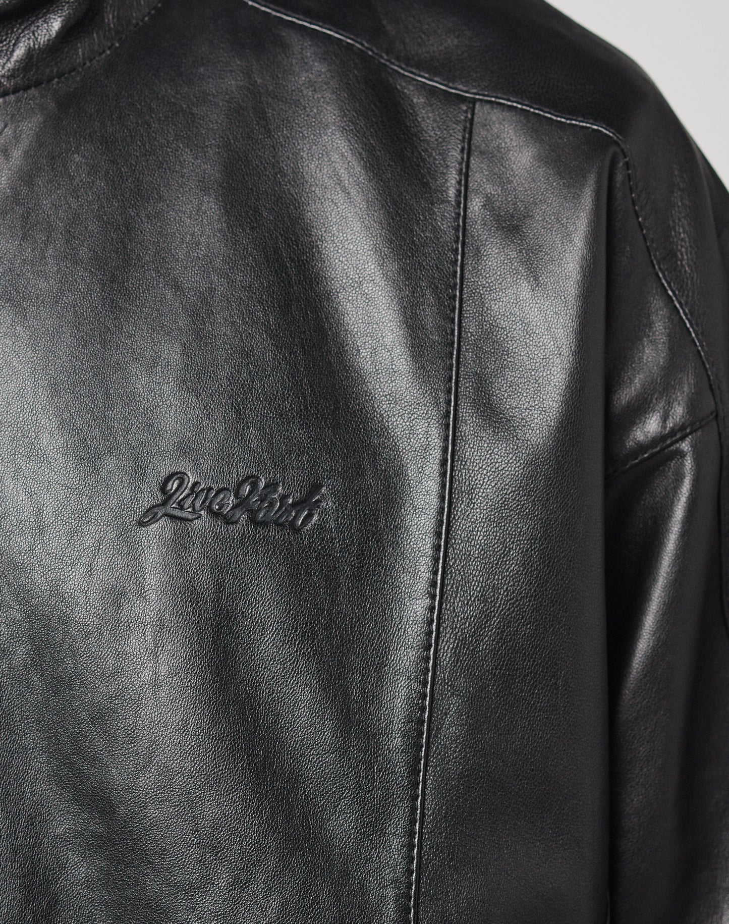 Close-up of the LIVE FAST DIE YOUNG Live Fast Leather Trackjacket, made from 100% leather, featuring a subtle 2nd Shot embossed logo on the left chest, with visible seams and a smooth leather texture.