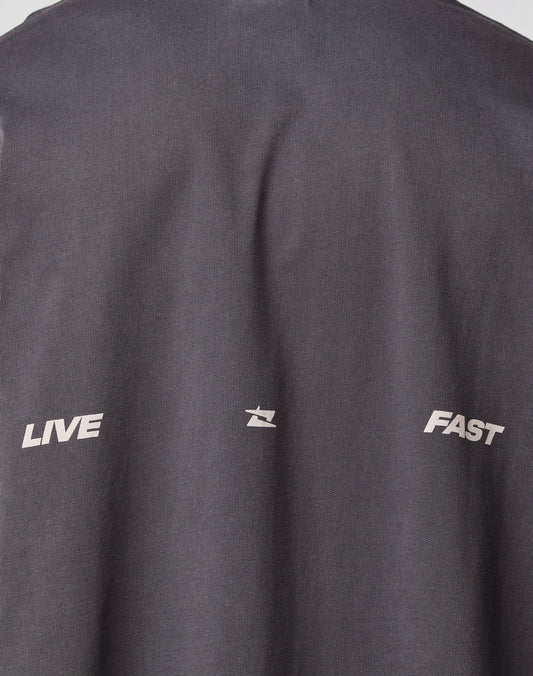 Close-up of the backprint on the dark gray Live Fast Cropped Oversized Tee by LIVE FAST DIE YOUNG, showing LIVE and FAST in white, separated by a small abstract white symbol.