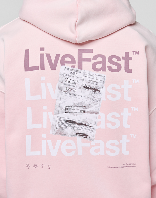 The Basic Evidence Hooded Zip by LIVE FAST DIE YOUNG is a light pink, oversized hoodie with bold LFDY branding, "LiveFast" in white and purple on the back, a worn shipping label graphic, plus small icons and website details at the bottom.