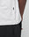Close-up of a person wearing the LIVE FAST DIE YOUNG Basic Trademark Tee—a white, 100% Baumwolle oversized t-shirt with a small black side tag. Paired with black pants and a hand near the pocket for a minimal look.