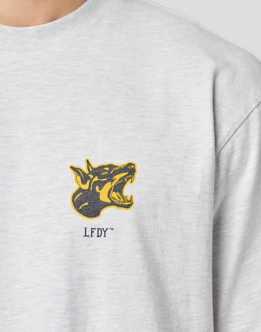 The LFDY Circle Dog Tee by LIVE FAST DIE YOUNG is a light gray oversized t-shirt with a graphic of a snarling black and yellow dog’s head above the LFDY™ logo on the left chest, made from 100% Baumwolle for comfort.
