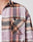 A close-up of a person wearing LIVE FAST DIE YOUNG’s Loose Summer Flannel—a 100% cotton plaid shirt in pink, orange, and black with a chest pocket LFDTY label—layered over a white undershirt.
