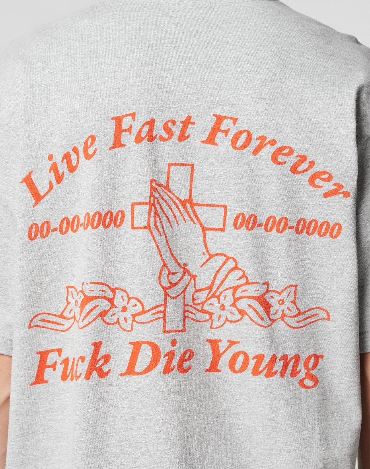 The LFDY Praying Tee by LIVE FAST DIE YOUNG is a gray oversized cotton T-shirt with orange text and a praying hands graphic over a cross with flowers, reading: “Live Fast Forever, 00-00-0000 00-00-0000, Fuck Die Young.”.