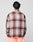 Seen from behind, a person with short, wavy dark hair wears the LIVE FAST DIE YOUNG Loose Summer Flannel—an oversize-fit shirt in pink, brown, and black plaid made from 100% Baumwolle—paired with light pink pants against a plain background.