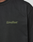 A close-up of the LIVE FAST DIE YOUNG Basic 210 Tee, an oversized black t-shirt made from 100% Baumwolle, featuring "LiveFast" in olive green on the left chest.