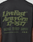 A close-up of the Basic 210 Tee by LIVE FAST DIE YOUNG shows the back of a black t-shirt with bold olive-green "LiveFast Army Grn 17-0517" text and smaller details. Made from 100% Baumwolle, it features an oversized fit with distinctive front and back prints.