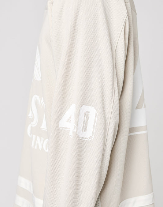 The LFDY Hockey Jersey by LIVE FAST DIE YOUNG features an oversized beige fit, white stripes, and the number 40 on the sleeve. Only its side and arm are visible against a plain backdrop. Made from soft polyester.