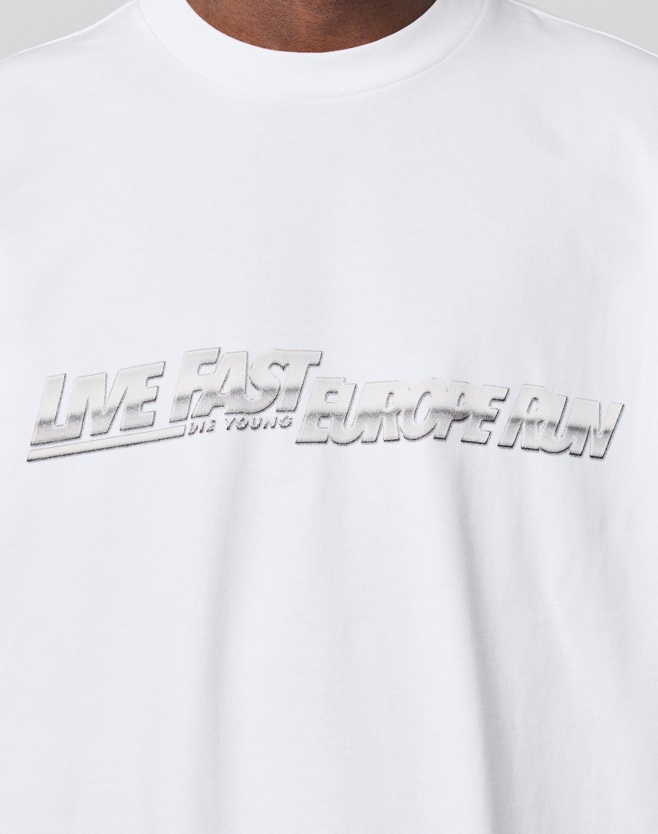Close-up of the LIVE FAST DIE YOUNG LFDY Europe Run Tee, a white 100% cotton t-shirt with bold metallic silver 3D EUROPE RUN lettering across the chest and an oversized fit for a modern look.