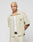 A person with short, bleached blonde hair wears the LFDY Twill Shirt by LIVE FAST DIE YOUNG in beige cropped oversize fit, paired with matching pants and a white tank top, standing against a plain light background with hands behind their back.