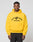 A man wearing a bright yellow LIVE FAST DIE YOUNG Live Fast Beware Hooded with LIVE FAST BEWARE and a fierce animal graphic on the front stands against a plain light gray background.