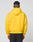 A person faces away from the camera, wearing a bright yellow LIVE FAST DIE YOUNG Live Fast Beware Hooded and dark pants against a plain light gray background.