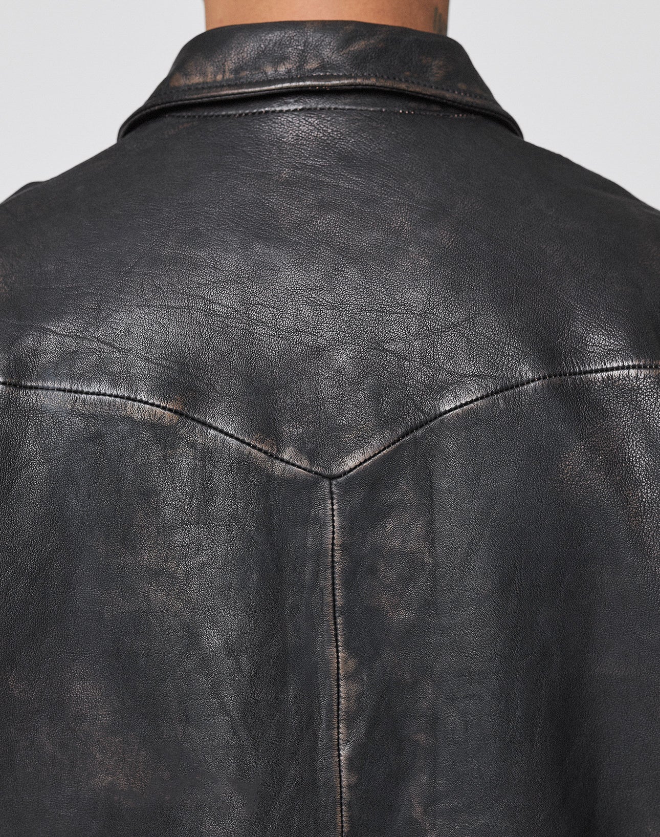 Close-up of the back of the LFDY Leather Jacket by LIVE FAST DIE YOUNG, showing the dark, distressed leather texture, visible seams, and collar with signature LFDY Reißverschluss from shoulders to mid-back.