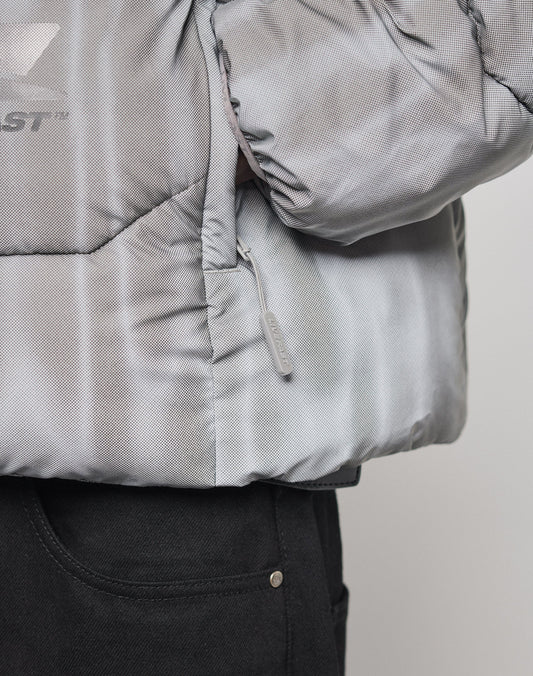 Close-up of the light gray Live Fast Puffer Jacket by LIVE FAST DIE YOUNG, featuring wasserabweisend finish, subtle stitched lines, branded piping at the hood opening, a side zipper, and a partially visible logo above the black pants pocket.