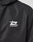Close-up of the LIVE FAST DIE YOUNG Live Fast Performance Rain Jacket in black, featuring a white graphic logo and LIVE FAST™ on the chest. The image highlights the logo, shoulder area, and its Regular Fit for comfort.