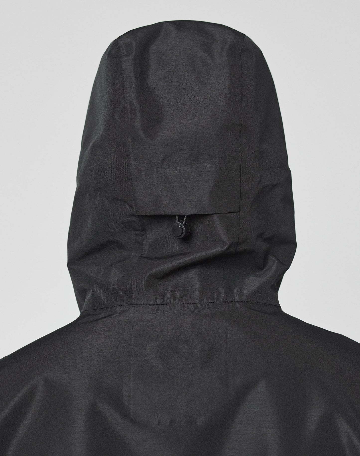 Close-up of the back of the LIVE FAST DIE YOUNG Live Fast Performance Rain Jacket in black, highlighting the hood with a small tab and loop detail. Features elastische Ärmelöffnung for added comfort and flexibility.