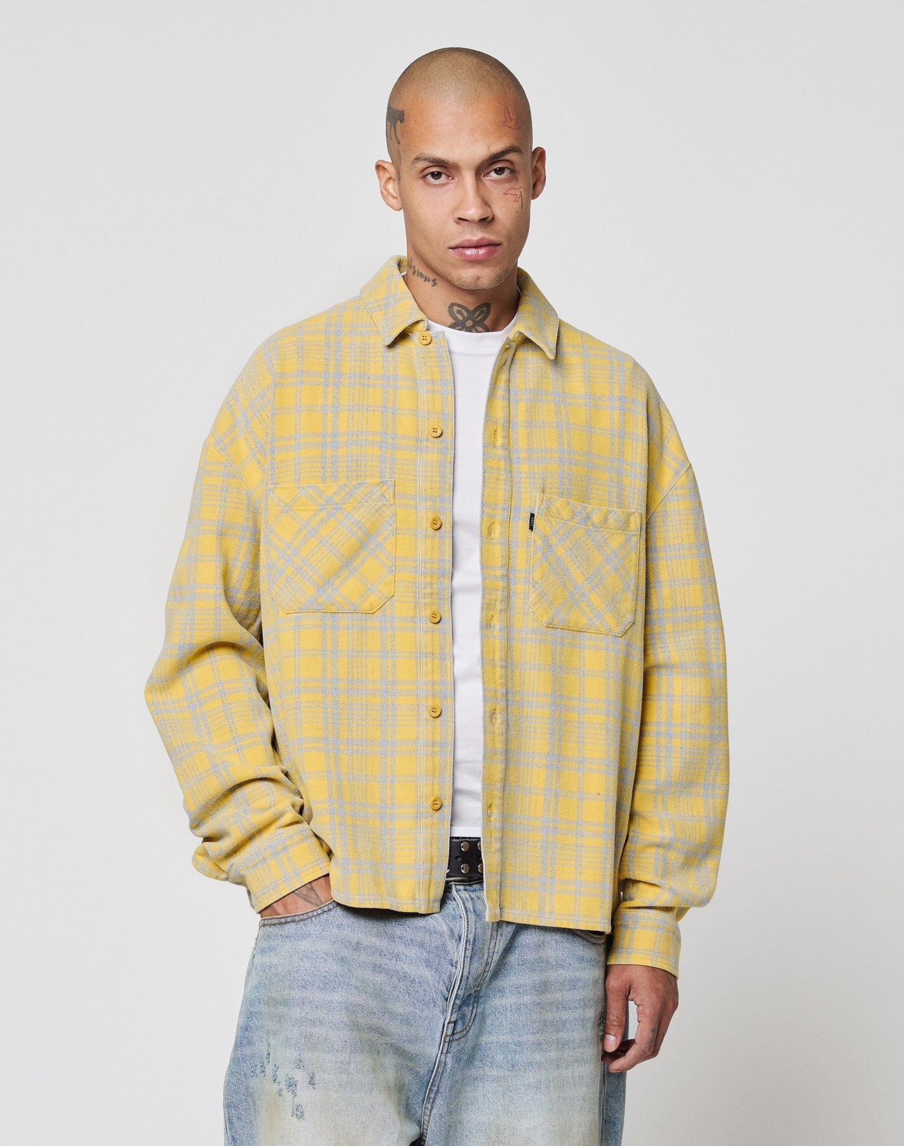 Wearing the LIVE FAST DIE YOUNG Vintage Flannel over a white tee and faded blue jeans, a person stands against a plain white background, looking at the camera with a neutral expression.