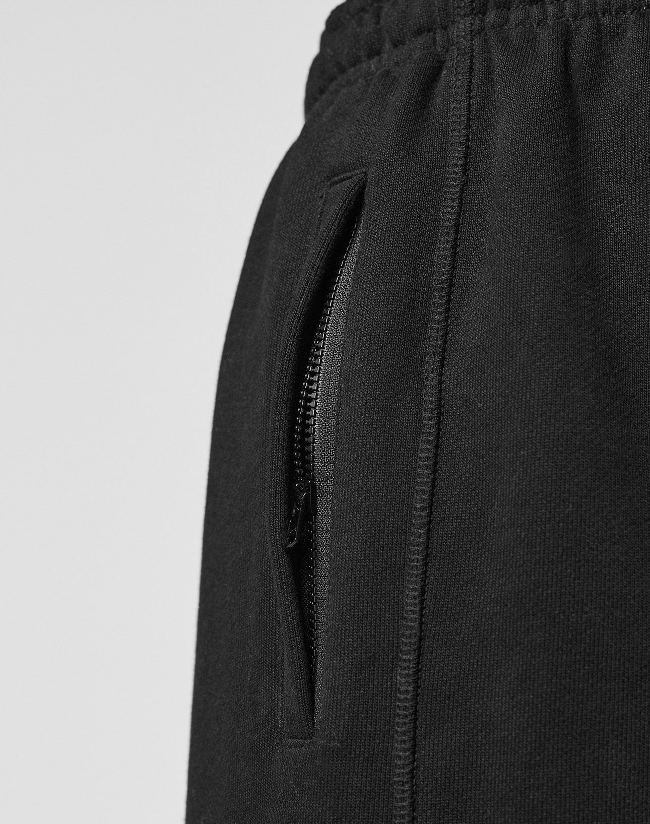 Close-up of the LIVE FAST DIE YOUNG Wide Cuff Jogger in black, featuring an elastic waistband, vertical zippered side pocket, and soft French Terry fabric for a textured look and comfortable wide fit.