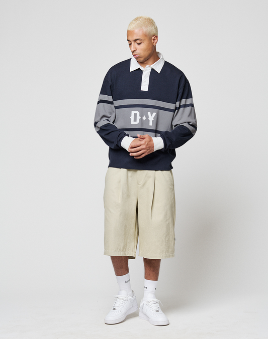 A person with short blond hair wears a LIVE FAST DIE YOUNG LFDY Striped Polo, beige Baumwoll-Twill knee-length shorts, white socks, and white sneakers, standing against a plain white background.