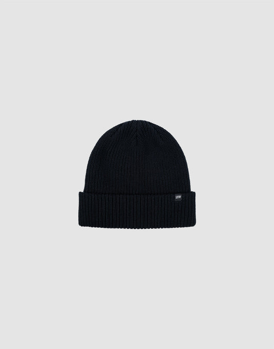 The LIVE FAST DIE YOUNG Double Rib Knit Beanie in black features a ribbed texture, folded brim, and a small black tag with white text, all displayed on a plain light gray background for a voluminous look. 