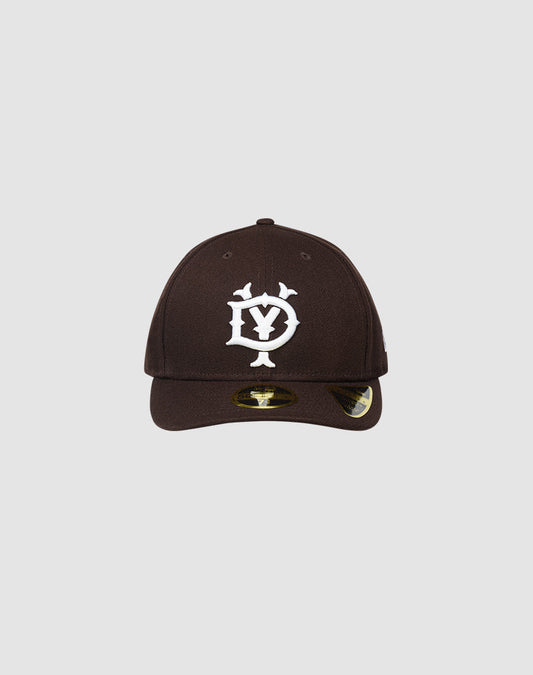 The LFDY X NEW ERA 59FIFTY LOW PROFILE by LIVE FAST DIE YOUNG is a black fitted cap with a white stylized DY logo, low profile silhouette, curved brim with shiny sticker, shown on a plain light gray background. 