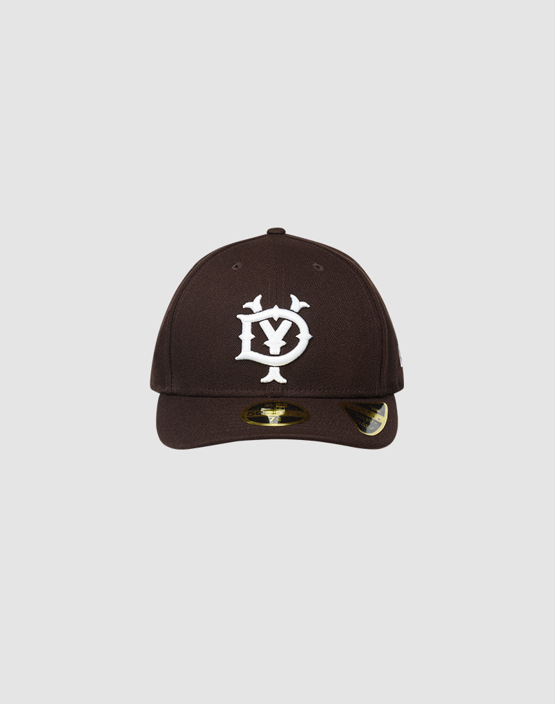 The LFDY X NEW ERA 59FIFTY LOW PROFILE by LIVE FAST DIE YOUNG is a black fitted cap with a white stylized DY logo, low profile silhouette, curved brim with shiny sticker, shown on a plain light gray background.| plain