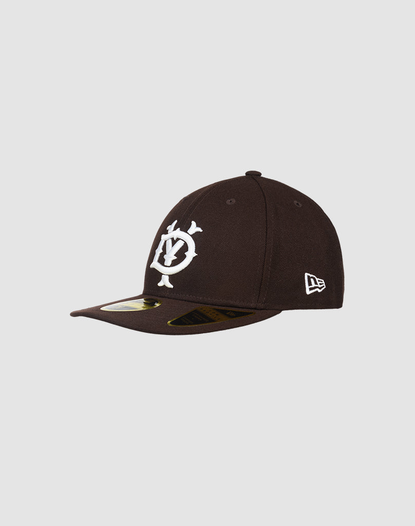 The LFDY X NEW ERA 59FIFTY LOW PROFILE by LIVE FAST DIE YOUNG is a black fitted cap with a flat brim, large white front logo, small white New Era side logo, and a gold visor sticker. Displayed on a plain light gray background.