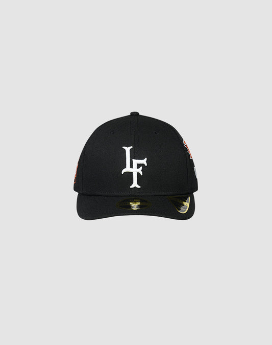 The LFDY X NEW ERA 59FIFTY LOW PROFILE by LIVE FAST DIE YOUNG is a black fitted cap with a white LF logo embroidered on the front, shown against a plain light gray background. A sticker appears on the low profile brim. 