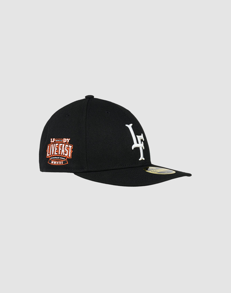 The LFDY x New Era 59FIFTY Low Profile cap by LIVE FAST DIE YOUNG features a black design with a white LF logo on the front and an orange LIVE FAST patch on the side, shown on a plain gray background.