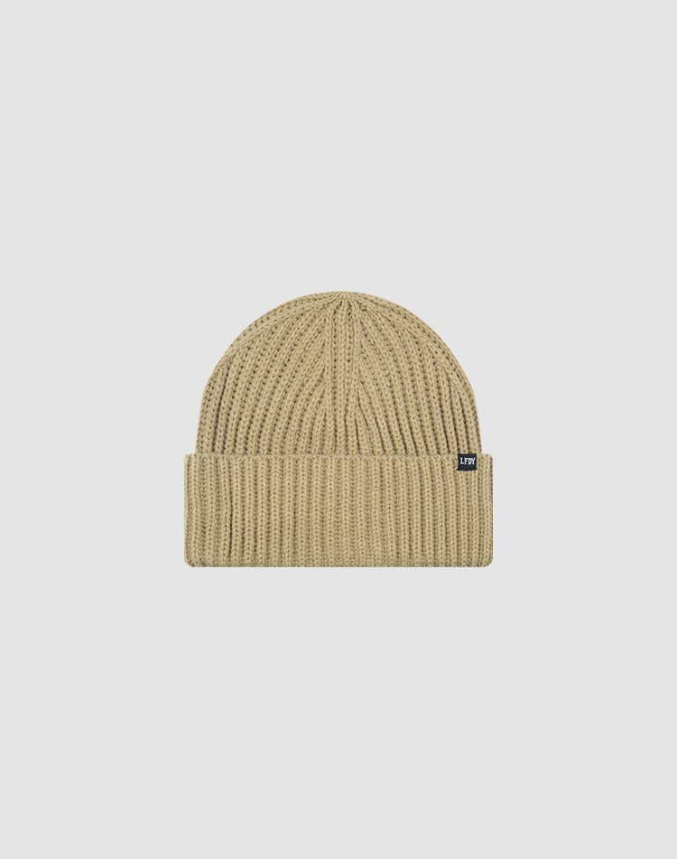 The LIVE FAST DIE YOUNG Rib Knit Beanie is a beige, one size hat with ribbed knit, folded cuff, and a small black Flag-Label tag on the side, made from cozy Polyamid and shown against a plain white background.