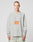 A person with short hair wears the LFDY Sports Longsleeve by LIVE FAST DIE YOUNG, featuring Raglan sleeves and an orange LIVE FAST graphic on light gray, paired with light-colored pants against a plain background.