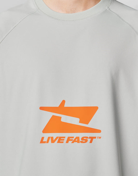 The LFDY Sports Longsleeve by LIVE FAST DIE YOUNG features a light gray color, an abstract orange graphic, and bold LIVE FAST™ text on the chest, all in an oversize fit for a relaxed, modern style.