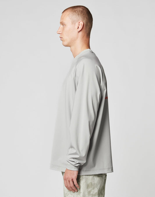 A person with short hair stands in profile, facing left, wearing a LIVE FAST DIE YOUNG LFDY Sports Longsleeve with Raglan sleeves and light pants against a plain light background.