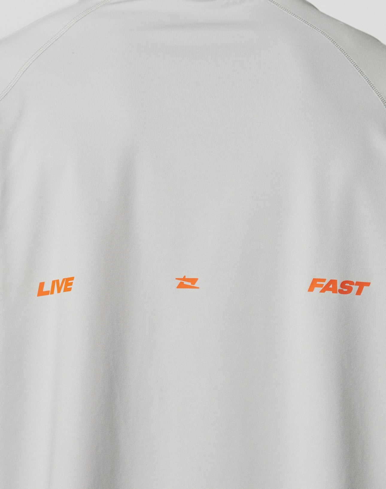 The back of the LFDY Sports Longsleeve by LIVE FAST DIE YOUNG features flatlock seams and LIVE and FAST in orange capitals, split by a small orange star. Oversize fit in light gray adds extra comfort.