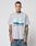 A man with tattoos and short hair wears the LFDY Crash Kid Tee by LIVE FAST DIE YOUNG, a light grey regular fit T-shirt featuring a car graphic and LIVE FAST text. He stands against a plain white background, looking at the camera.