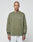 A person with a shaved head and neck tattoos wears the olive green LIVE FAST DIE YOUNG Basic Longsleeve with a white chest logo and light gray pants, standing against a plain light background.