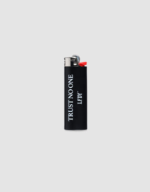 The LFDY Trust No One Lighter by LIVE FAST DIE YOUNG is a black BIC J26 with a chrome cap, TRUST NO ONE in white vertically, LF DY below, set on a plain light gray background. Bis zu 3000 Zündungen möglich. 