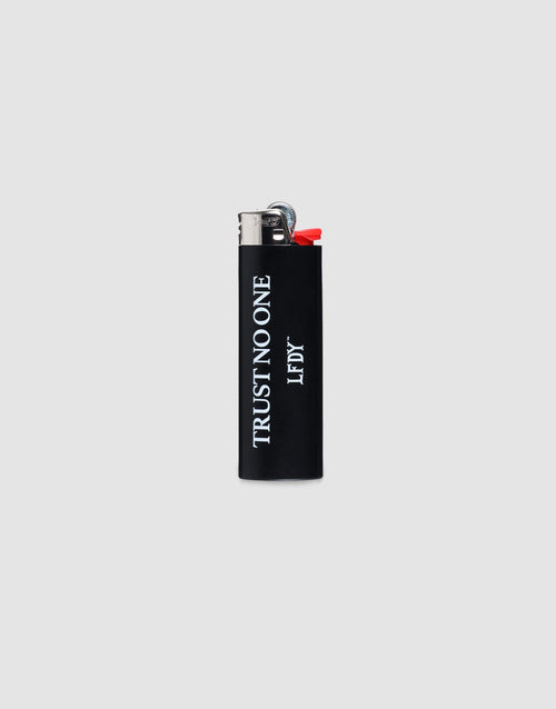 The LFDY Trust No One Lighter by LIVE FAST DIE YOUNG is a black BIC J26 with a chrome cap, TRUST NO ONE in white vertically, LF DY below, set on a plain light gray background. Bis zu 3000 Zündungen möglich. 