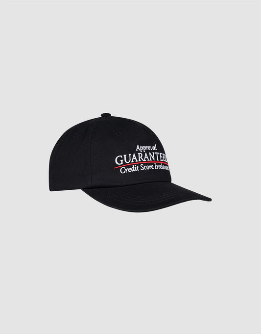 The LFDY Guaranteed Cap by LIVE FAST DIE YOUNG is a black unstructured 5-panel cap made from 100% polyester with a snap closure. It features white and red "Approval GUARANTEED. Credit Score Irrelevant." embroidery on the front, shown on a plain light gray background.