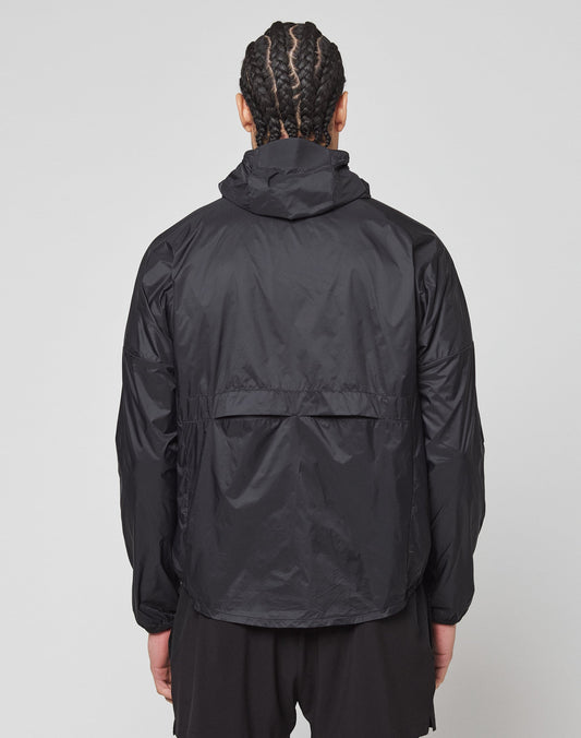 A person with braided hair is seen from the back wearing the LIVE FAST DIE YOUNG Live Fast Performance Running Jacket in black and black shorts, against a plain light background.