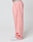 A person wearing LIVE FAST DIE YOUNGs Basic Wide Jogger in light pink with an elastic waistband and white sneakers, standing sideways against a plain white background.